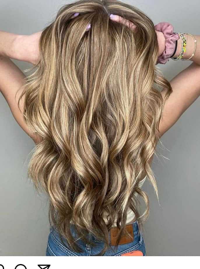 Woman with wavy, highlighted blonde hair from the back.