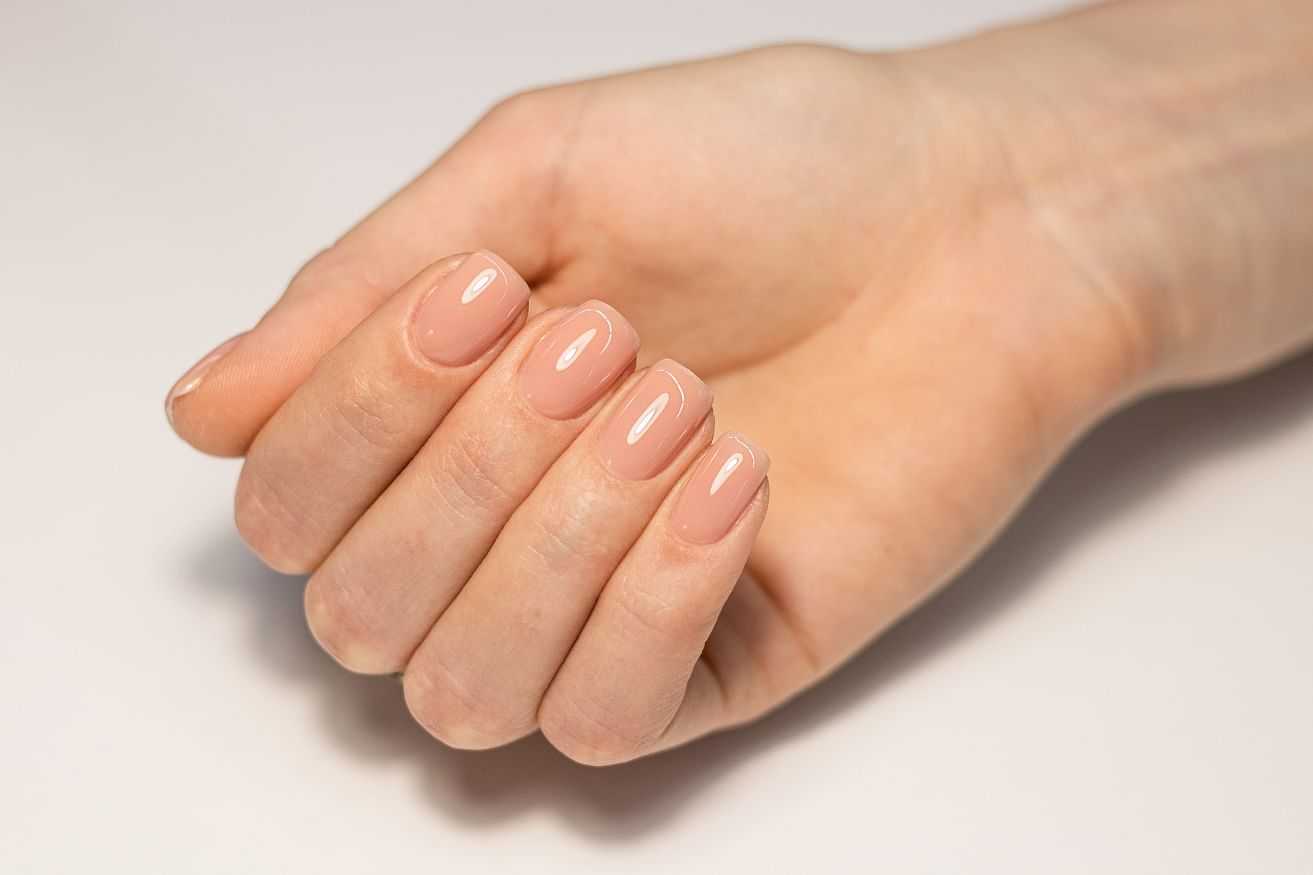 Close-up of a hand with neatly manicured nails in a light pink shade.